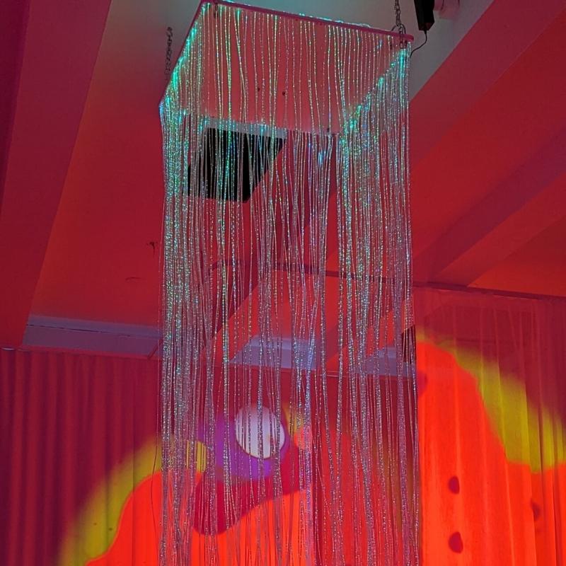 TFH Fibre Optic Waterfall ceiling view showing the 24-inch mirrored square shelf and 200 red-lit fibre optic tails cascading downward in a sensory room