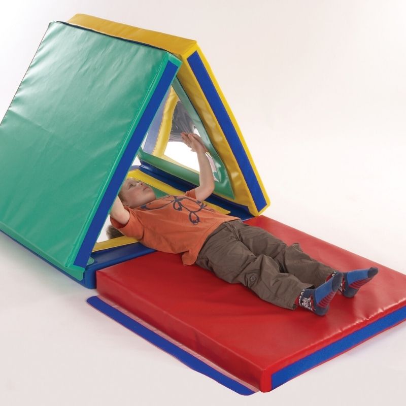 Child lying inside the TFH Giant Folding Mirror Den surrounded by reflective mirror panels, using the den as a calm, contained sensory retreat