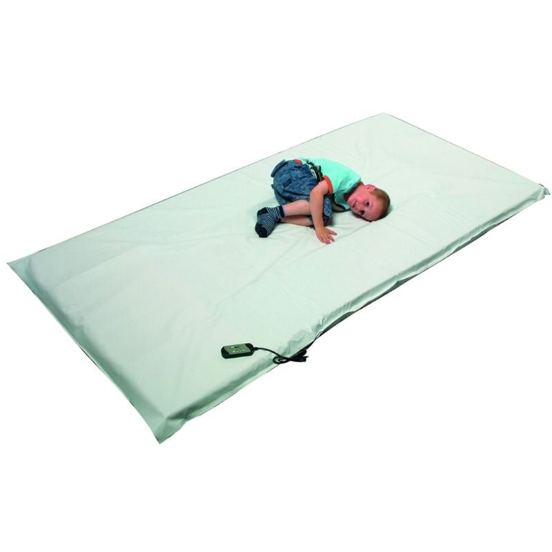 Child lying on the TFH Giant Vibrating Floor Pad showing the full 96 x 48 inch wipe-clean vinyl surface in use for full-body vibration therapy and proprioceptive input