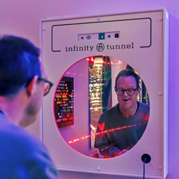 Smiling adult looking into the TFH Interactive Infinity Tunnel as red LED light trails respond to his voice, a sound-responsive optical illusion wall panel