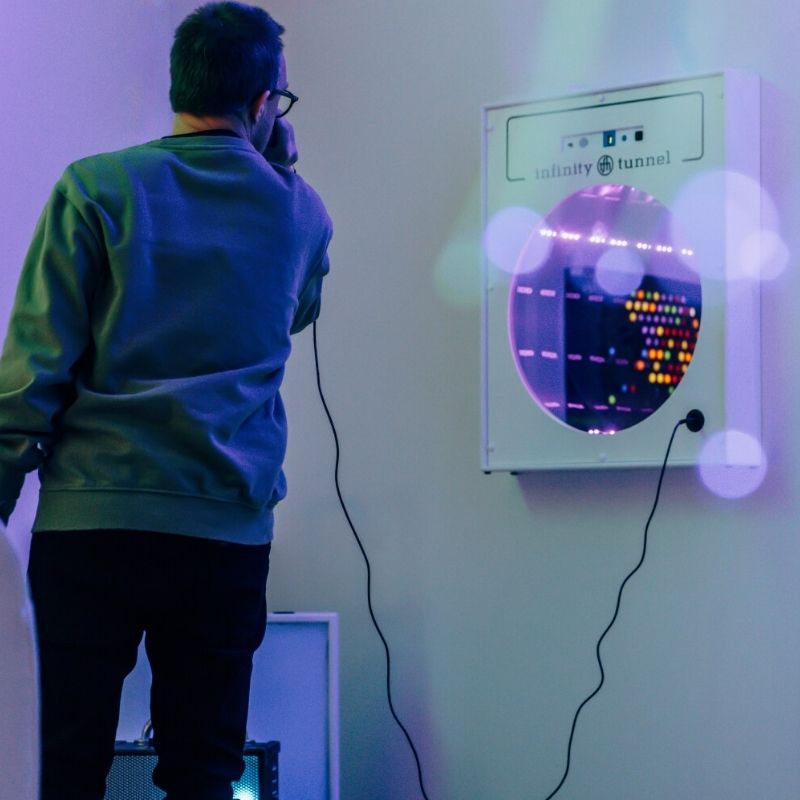 TFH Interactive Infinity Tunnel and Microphone installed on a wall with an adult engaging with the sound-responsive optical illusion panel in a sensory room or therapy space