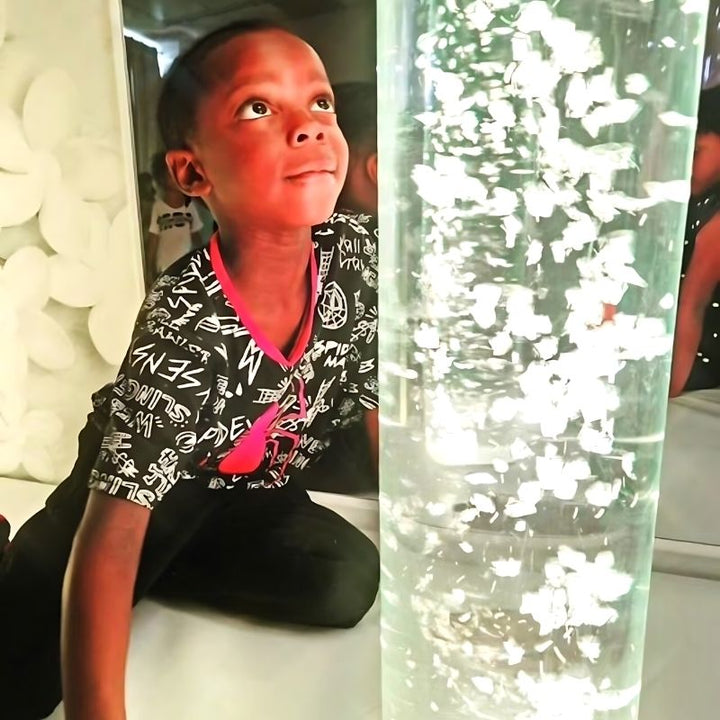 Child actively engaging with the TFH Interactive LED Bubble Tube in a sensory room setting