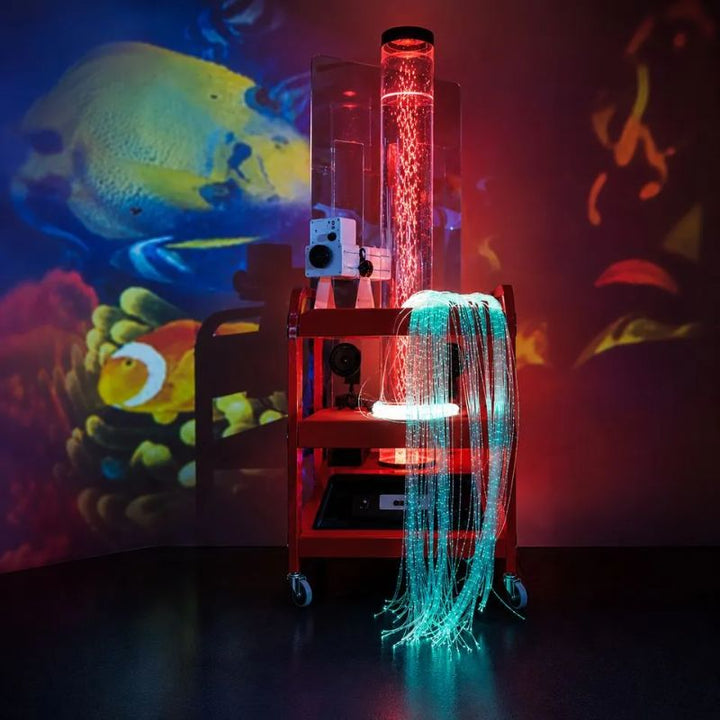 TFH Little Red Sensory Cart Deluxe Water projecting the included Tropical Fish effects wheel onto the walls, its red-lit bubble tube and teal fibre optic tails glowing on the portable sensory cart