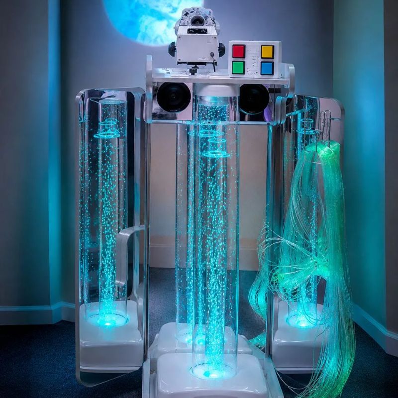 TFH Vecta Whirlwind Deluxe Mobile Sensory Station glowing teal, its waterless Hurricane Tube reflected in the side mirrors beside fibre optic tails, with the projector casting a moon scene onto the wall