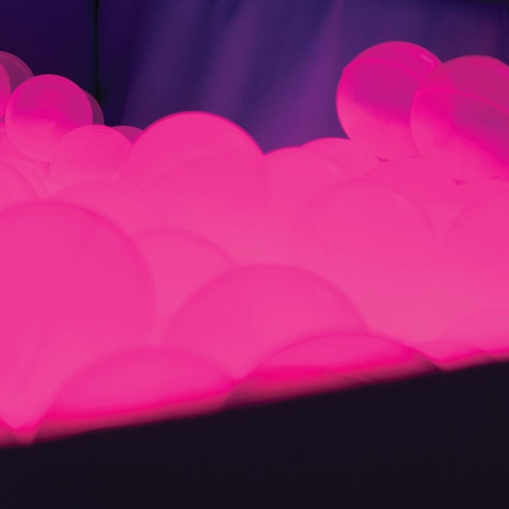 Close-up of TFH Light-Up Ball Pit translucent sensory balls glowing in pink LED light for visual sensory stimulation