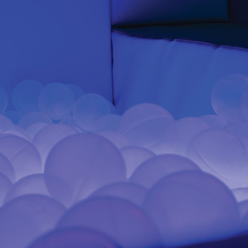 Close-up of TFH Large Light-Up Ball Pit translucent balls glowing in purple LED light showing proprioceptive ball pool depth