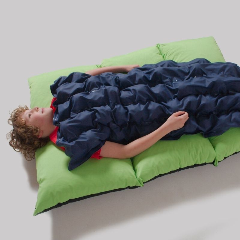 Second child using the TFH Sensory Pressure Vinyl Ball Pad lying down, demonstrating the full-body deep pressure and proprioceptive stimulation provided by the ball-filled pad