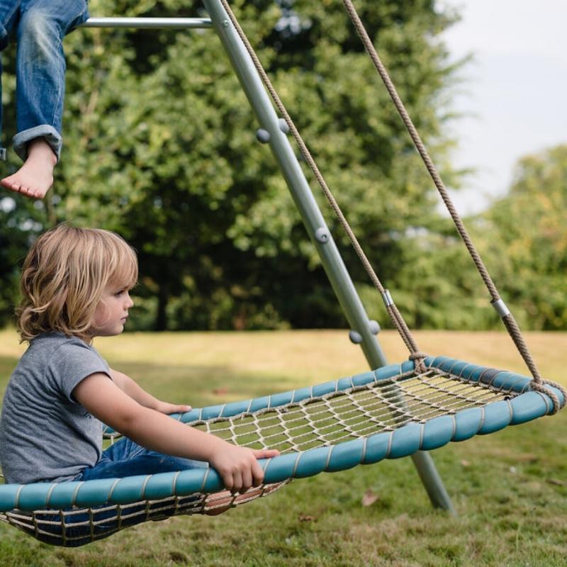 Child playing in the TFH Sky Cruiser Net Swing, a hammock-style sensory swing for vestibular input and sensory integration therapy