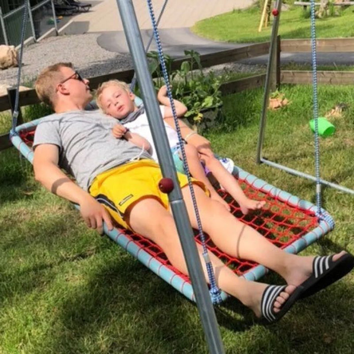 Father and child relaxing together in the TFH Sky Cruiser Net Swing outdoors, showing the 55" framed hammock sensory swing's room for shared vestibular rest