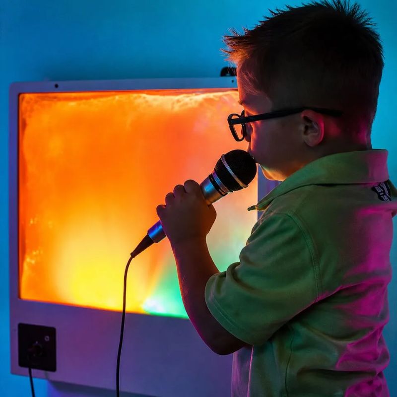 Boy singing into the included microphone as the TFH Sound to Light Interactive Panel glows orange and yellow, turning his voice into colour for vocalization play