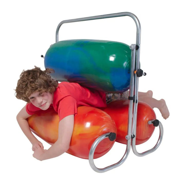 Smiling boy lying between the blue-green top bumper and orange lower bumpers of the TFH Sensory Squeeze Machine, enjoying calming full-body deep pressure input