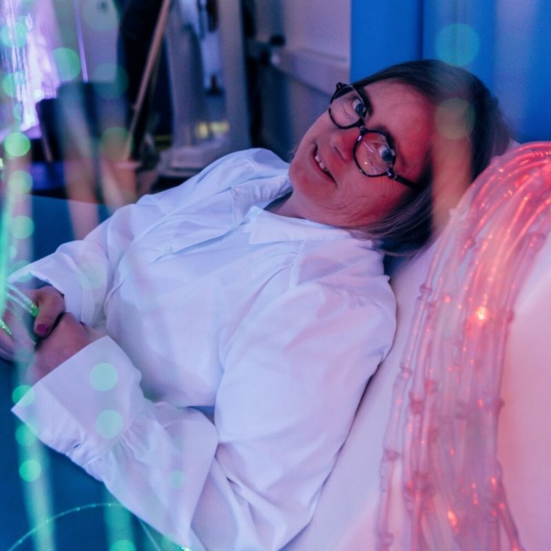 TFH Textured Light Spray with an adult lying down and resting with the knotted fibre optic tails, showing the calming proprioceptive and tactile sensory benefit of the textured light spray for relaxation and self-regulation
