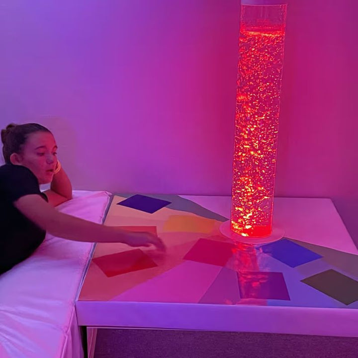 A student reaches to change colour on the TFH Touch-A-Color Podium as the bubble tube shifts to a warm red glow