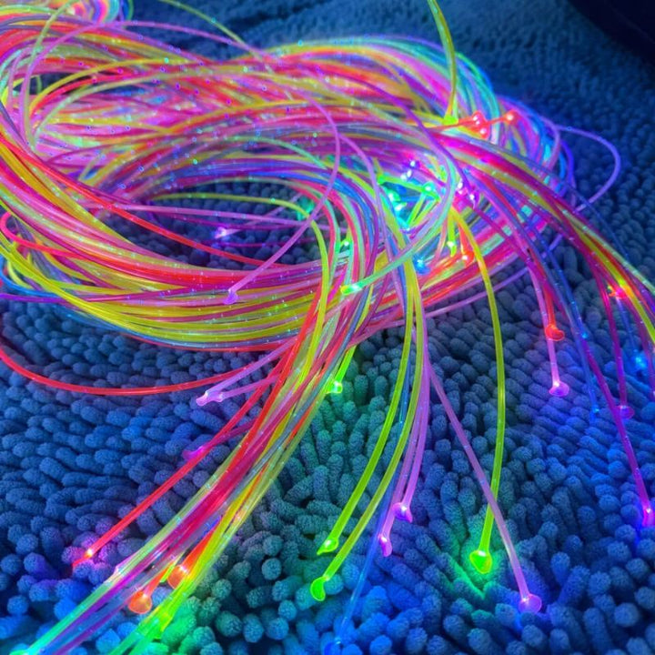 Multicolour TFH UV Fibre Optic Tails coiled across a blue textured mat, the 80" glowing strands spread out for hands-on counting, sorting and fine motor play