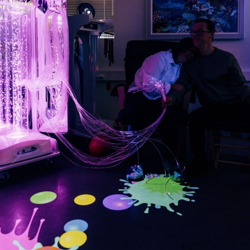 Two adults relaxing beside the TFH Vecta Budii mobile sensory cart, demonstrating its calming and therapeutic benefits for older adults and care home settings