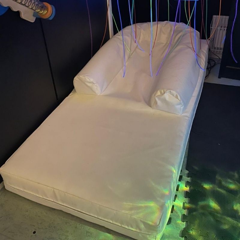 TFH Vibroacoustic Long Easy Floor Lounge landscape view showing the full-length reclining foam shape with rimmed edge, used as vibroacoustic therapy furniture for sensory rooms and therapy spaces
