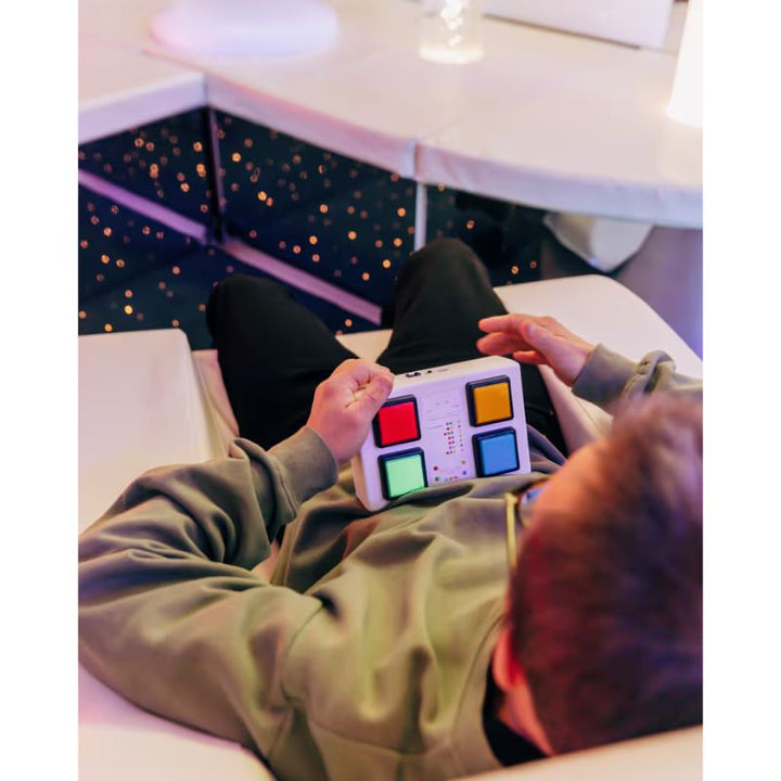 User pressing buttons on the TFH Wireless Colour Controller to change colours in a multi-sensory room environment