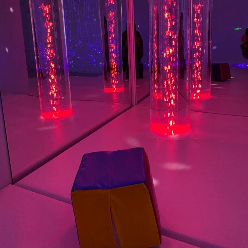 TFH Wireless Colour Controller Cube in a sensory room showing the cube controlling a TFH bubble tube in red LED light, demonstrating cause-and-effect colour control