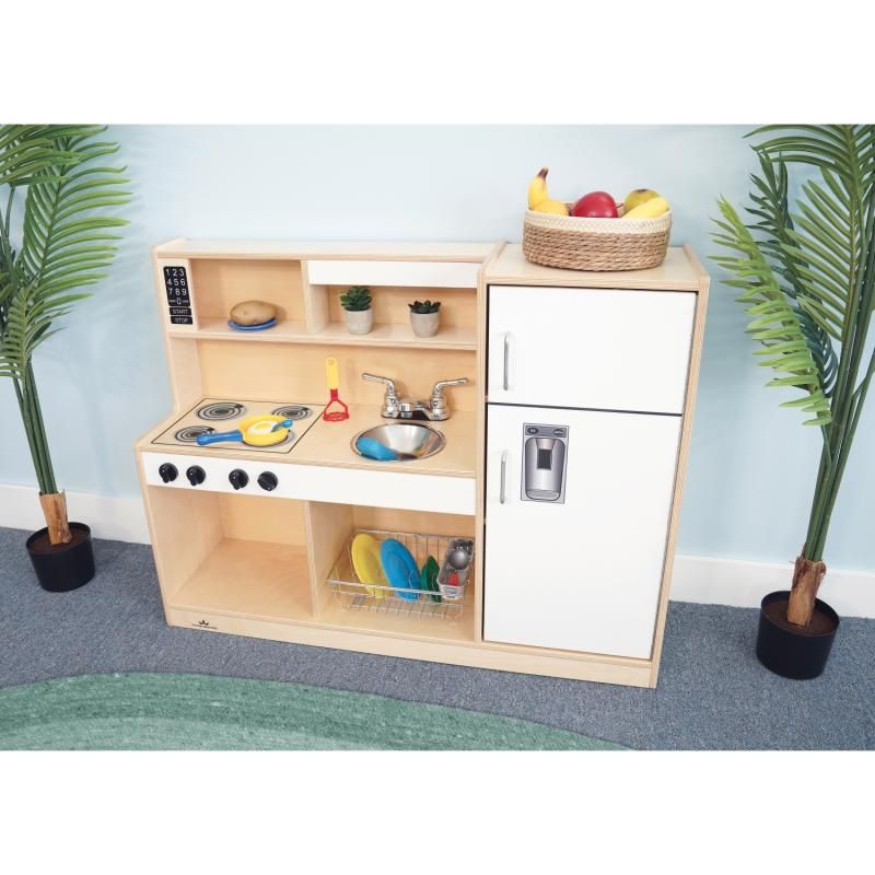 Whitney Brothers Let's Play Toddler Kitchen Combo in white, a wooden toddler play kitchen styled for dramatic play in a bright daycare classroom