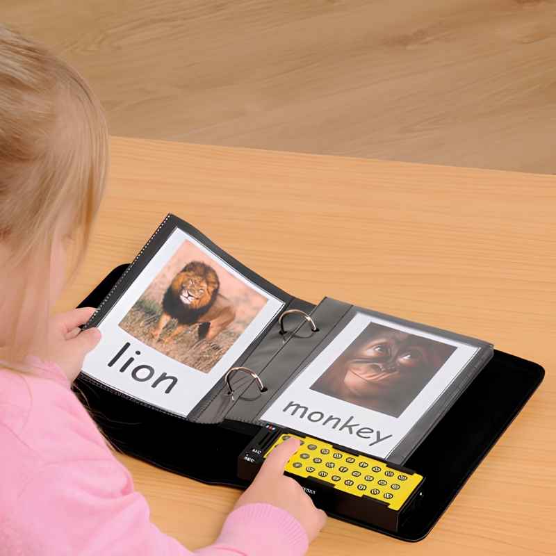 Young child pressing the numbered recordable buttons on the TTS A5 Talking Photo Album while looking at photo pages showing a lion and a monkey with word labels, a communication and literacy tool for early learners