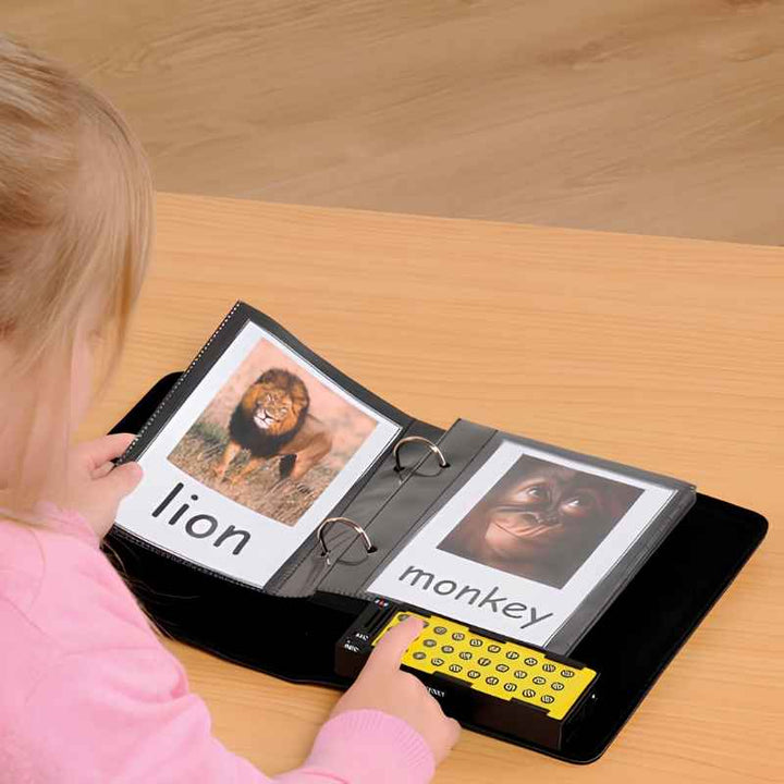 Young child pressing the numbered recordable buttons on the TTS A5 Talking Photo Album while looking at photo pages showing a lion and a monkey with word labels, a communication and literacy tool for early learners