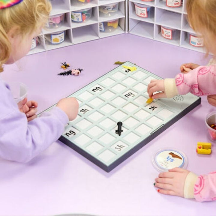 Two children using the TTS A3 Chatter Board Pro together in a classroom setting, writing on the dry-wipe recording tiles during a speaking and listening activity