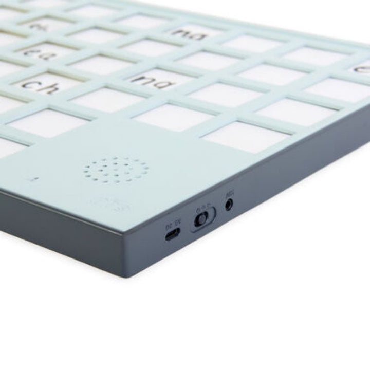 Close-up of the TTS A3 Chatter Board Pro bottom edge showing the built-in speaker, USB charging port, and headphone socket for private listening during communication activities