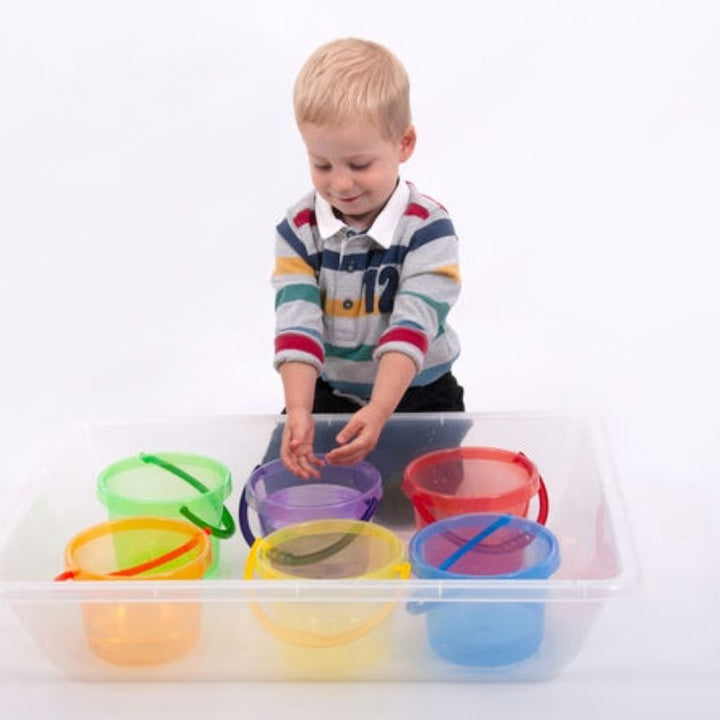 Boy using TTS Translucent Colour Buckets for sand and water sensory play, encouraging colour mixing, capacity concepts, and early mathematical thinking