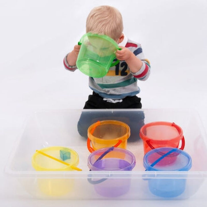 Child actively pouring and exploring with TTS Translucent Colour Buckets during tactile sensory play, supporting early years development through sand and water activities