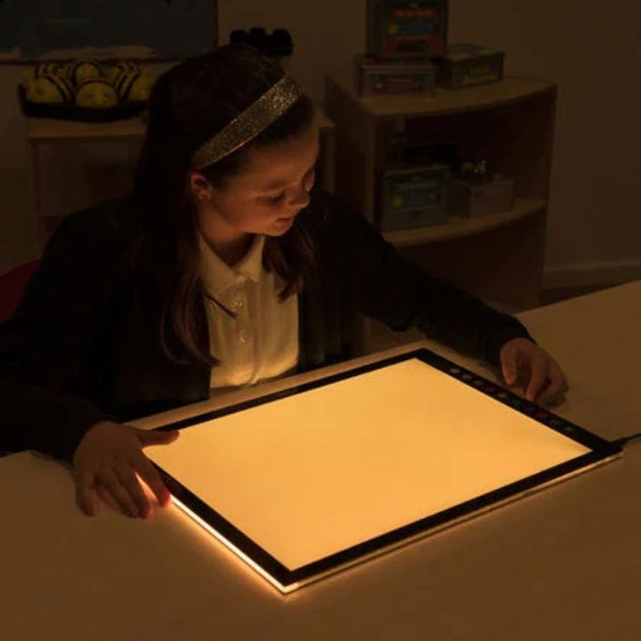 Girl using the TTS Colour Changing Light Panel in warm amber light mode, showing the adjustable LED surface for calm sensory and visual learning