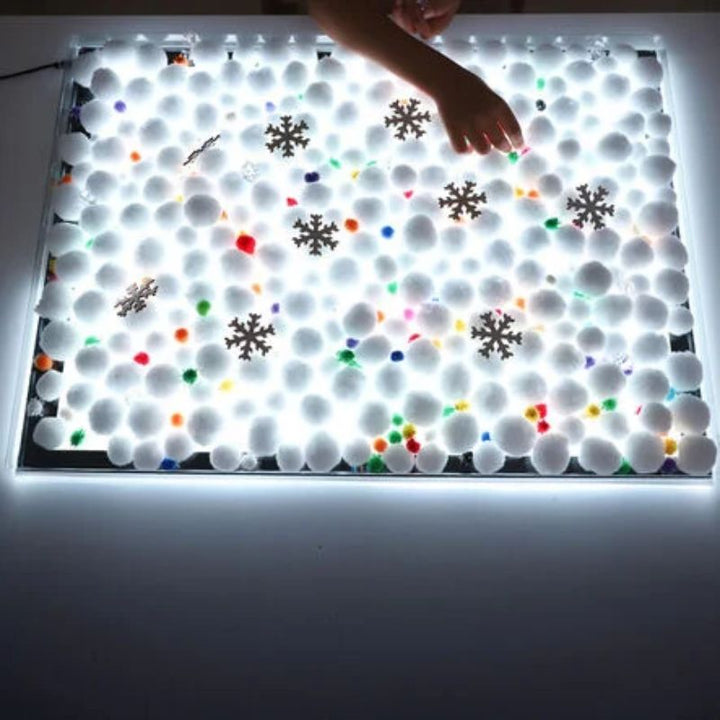 TTS Colour Changing Light Panel covered in white pom-poms and snowflakes, creating an illuminated winter sensory play scene for early years learning