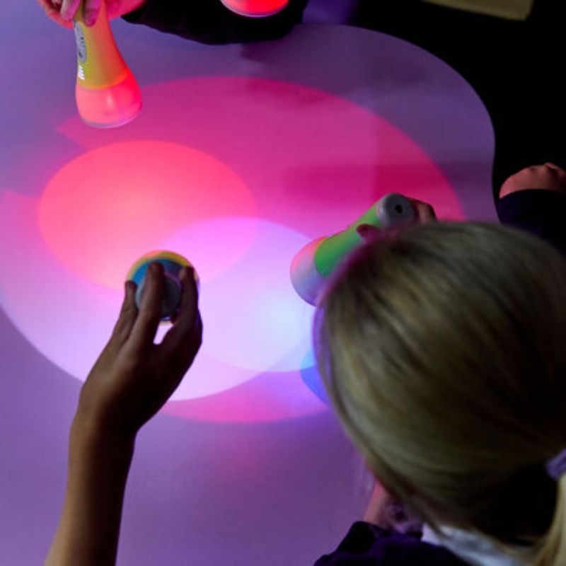 Overhead view of children using TTS Colour Changing Easi-Torches for colour mixing and sensory light experiments in a classroom or sensory room
