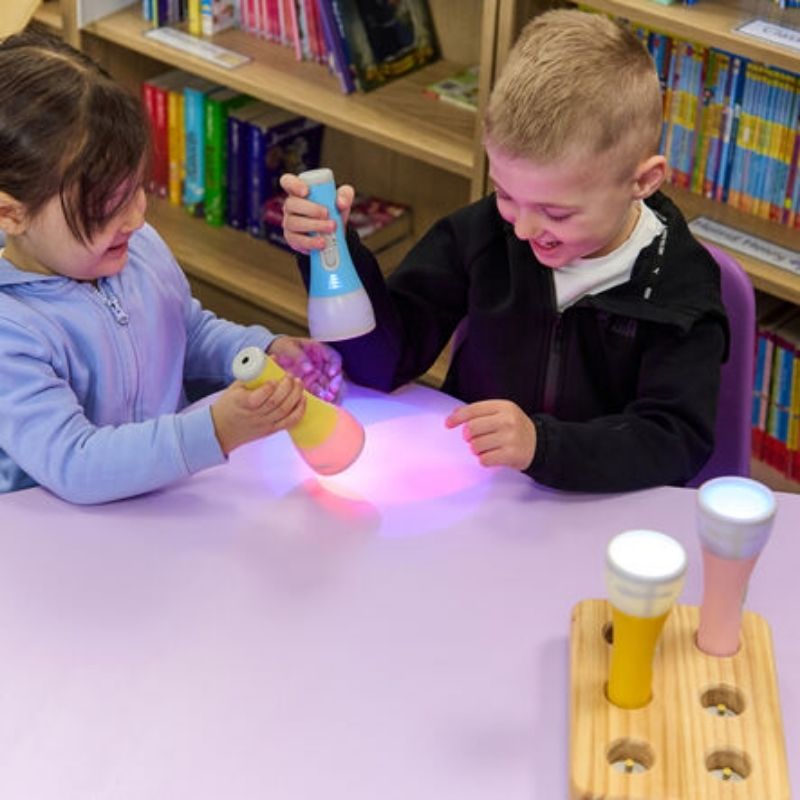 Two children engaged in a science learning activity with TTS Colour Changing Easi-Torches, exploring cause and effect with colour-changing LED light