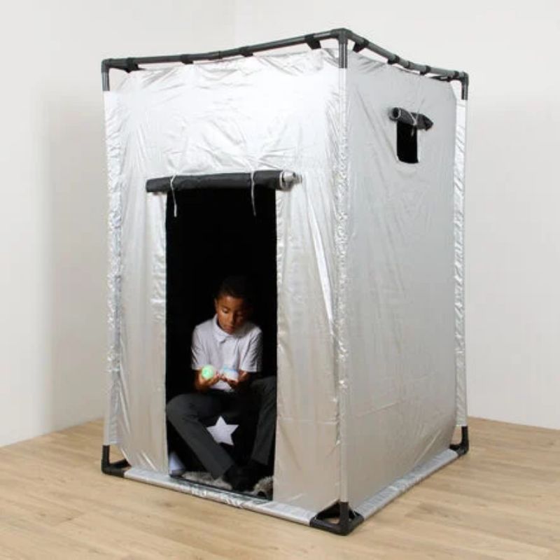 Boy sitting inside the TTS Giant Sensory Dark Den holding light-up sensory toys, showing the blackout interior for calm, focused sensory play