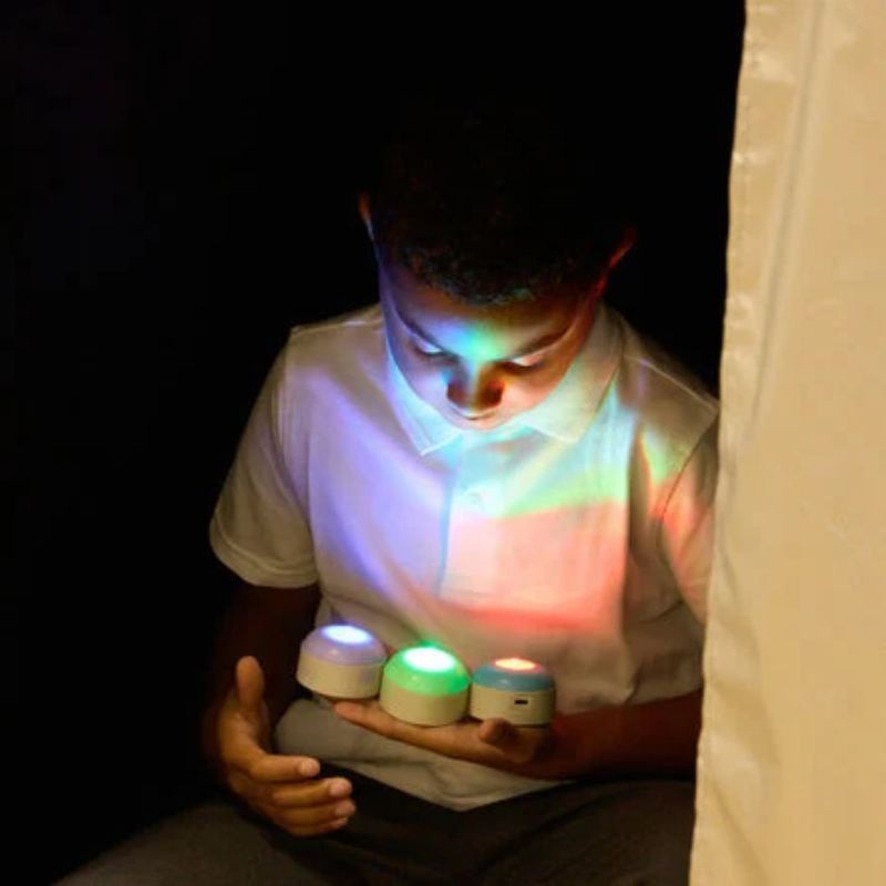 Boy holding colour-changing lights inside the TTS Giant Sensory Dark Den, with the total-blackout space making every glow stand out
