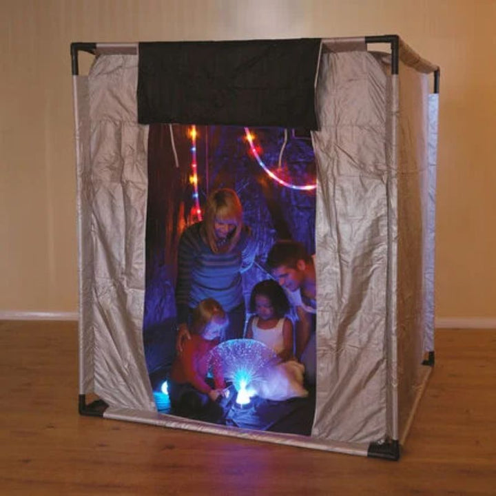 Adults and children inside the TTS Giant Sensory Dark Den in landscape orientation, exploring a fibre optic lamp and rope lights during group sensory play