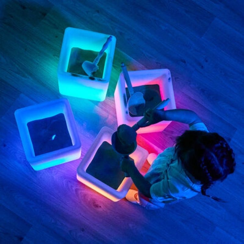 TTS Glow Cubes in use as sand and water play stations, demonstrating the waterproof design for messy sensory play activities