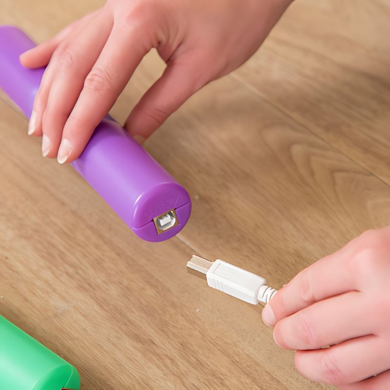 Close-up of the charging port on a TTS Light Up Glow Cylinder, showing the USB charging connection used to recharge the full set of 12 sensory LED toys