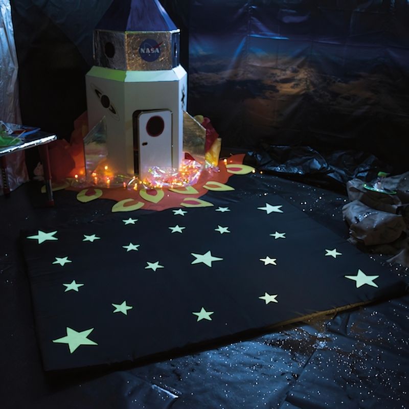 TTS Glow in the Dark Mat laid flat and glowing in a darkened sensory room, showing the full phosphorescent surface