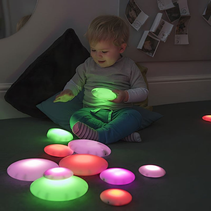 Boy stacking TTS Glow Pebbles to develop fine motor skills and cause-and-effect understanding through LED sensory play