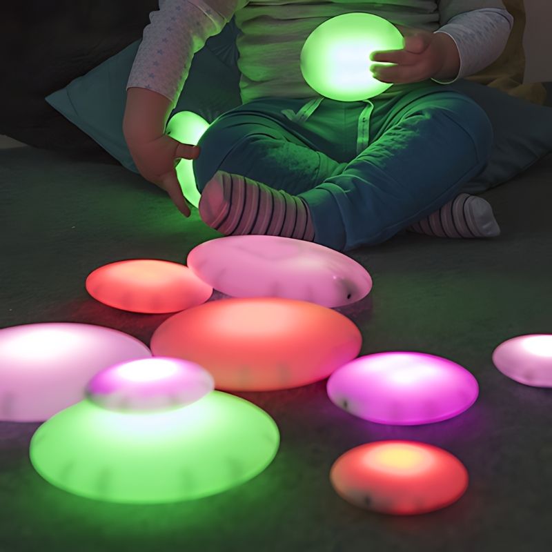 Close-up of TTS Glow Pebbles showing vibrant colour-changing LED illumination, suitable for sensory rooms, calm corners, and therapy spaces