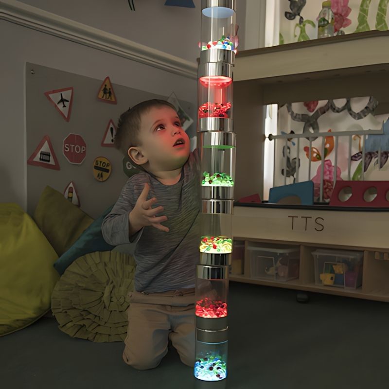 Young boy piling and stacking TTS Glow Roller Shakers during sensory play, exploring schema and cause-and-effect with illuminated light toys