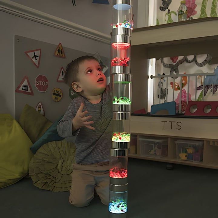 Young boy piling and stacking TTS Glow Roller Shakers during sensory play, exploring schema and cause-and-effect with illuminated light toys