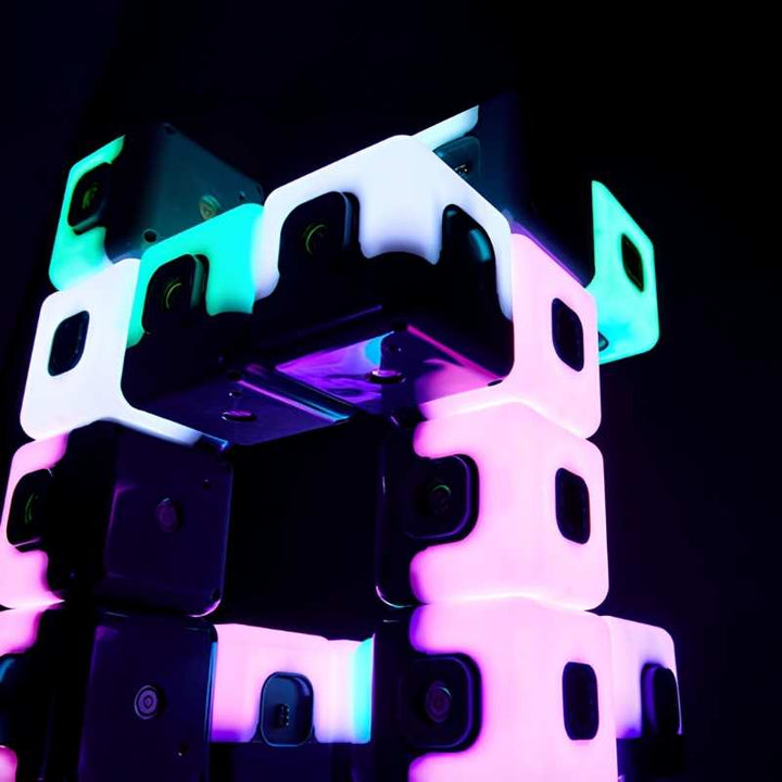 Close-up of TTS Glow Sequencing Cubes magnetically stacked in a tower, glowing in cyan, white and pink-purple, showing the magnetic connection points and large-cube format