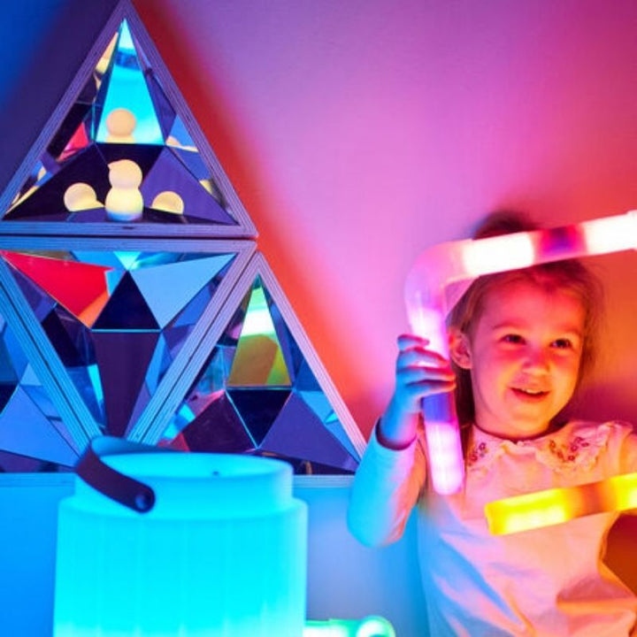 Child exploring reflections in the TTS Kaleidoscope Mirror with blue and red light hues, supporting visual sensory development