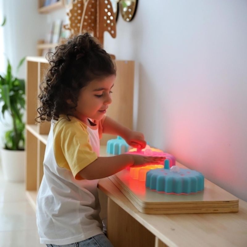 Child actively engaging with the TTS Light Up Cog Board on a desk, developing fine motor skills and hand-eye coordination