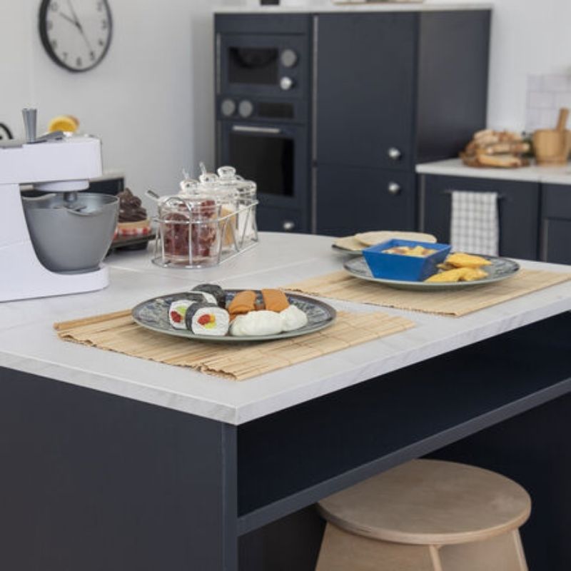 TTS Modern Living Kitchen Island Set styled as a role play dining area with play food, placemats and a stool, showing the full Modern Living navy kitchen collection in the background