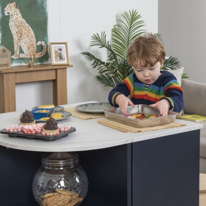 Young child independently exploring the TTS Modern Living Kitchen Island Set worktop with play food and baking props, building fine motor and cognitive skills through self-directed dramatic play
