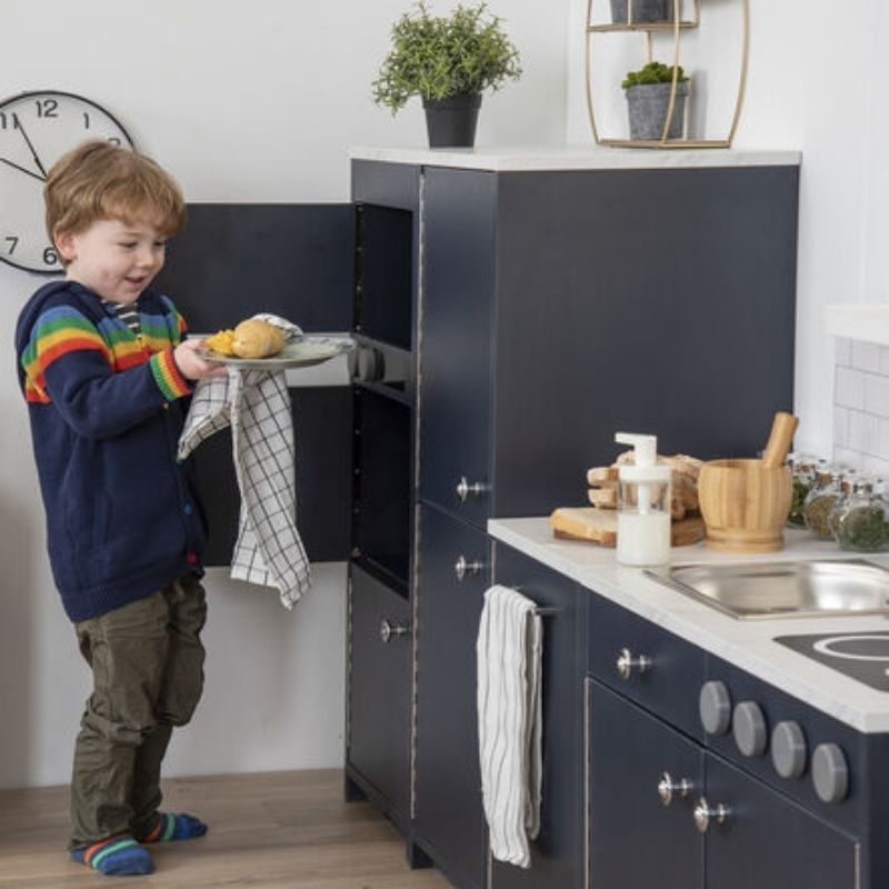 TTS Modern Living Oven and Microwave Unit navy detail view, showing the accessible storage cupboard and full-length safety hinges on this wooden play kitchen