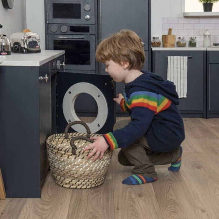 Child engaged in pretend play with the TTS Modern Living Washing Machine, a role play toy supporting fine motor skills and social development